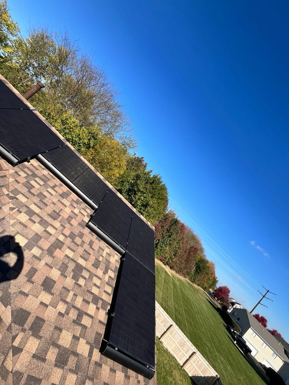 Solar panels along a roof edge under a clear blue sky