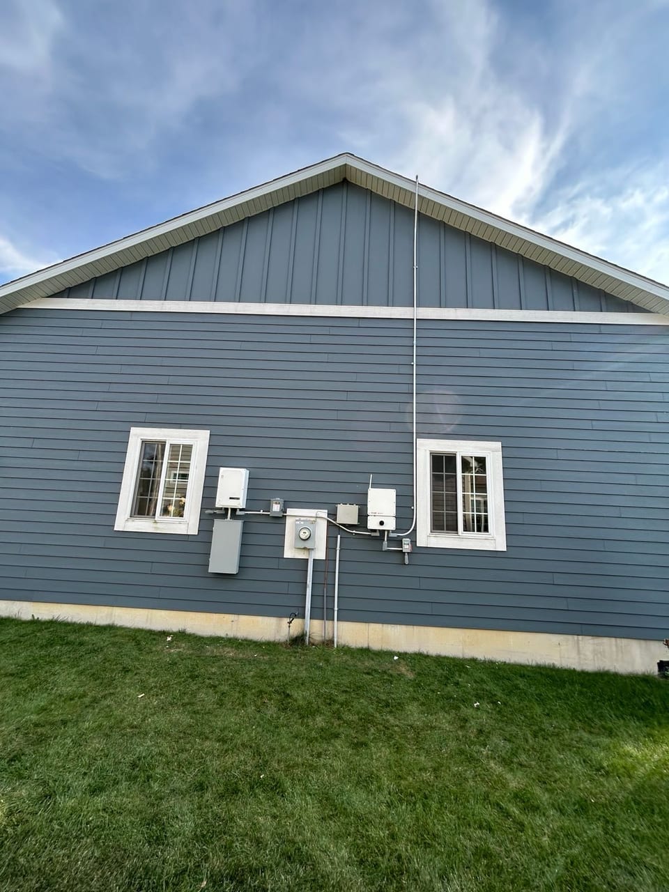 Home exterior with newly installed solar electrical equipment on the siding