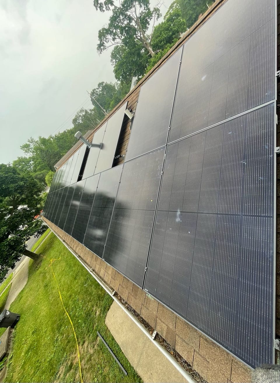 Solar panel array on a residential roof above a green lawn