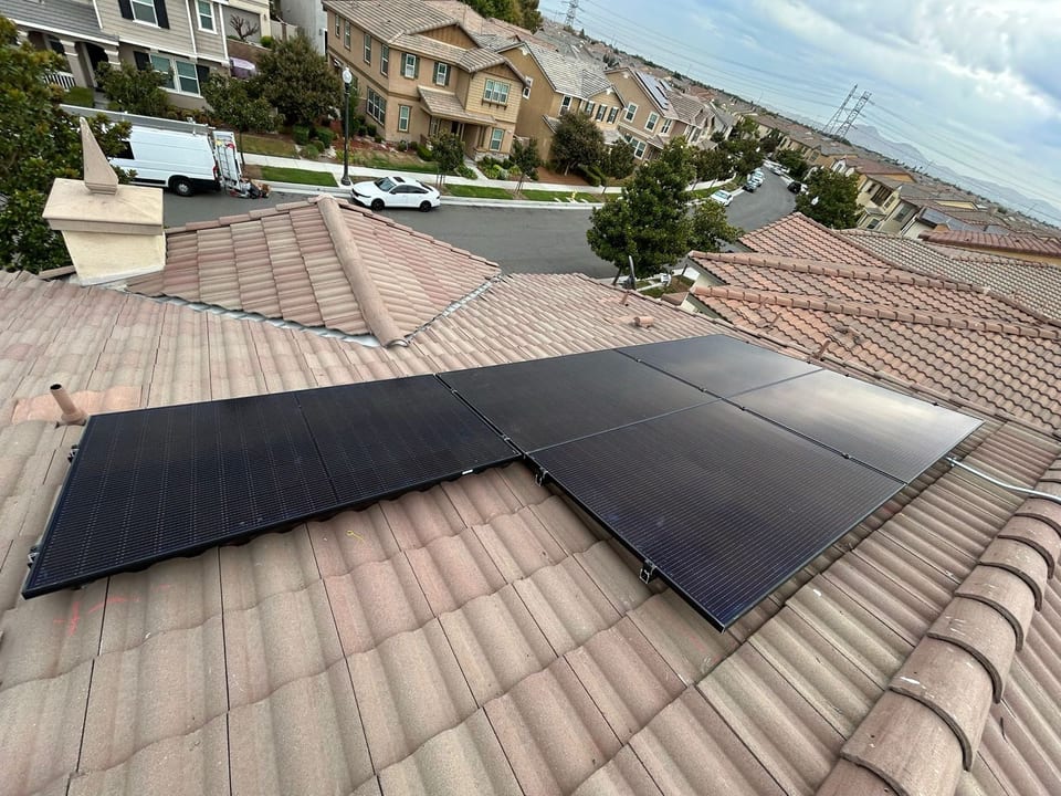 Large black solar array spanning a tile roof above a neighborhood