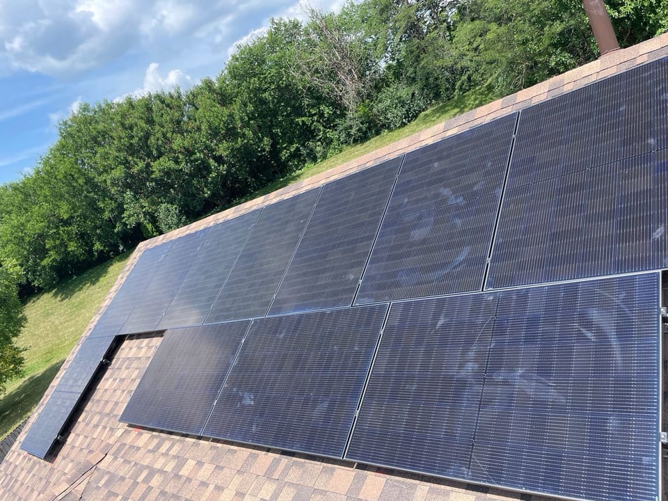 Black solar panel array on a tile roof under a clear sky