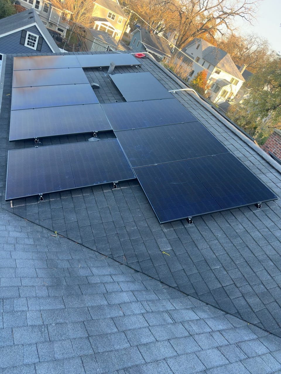 Solar array on a shingle roof surrounded by autumn trees