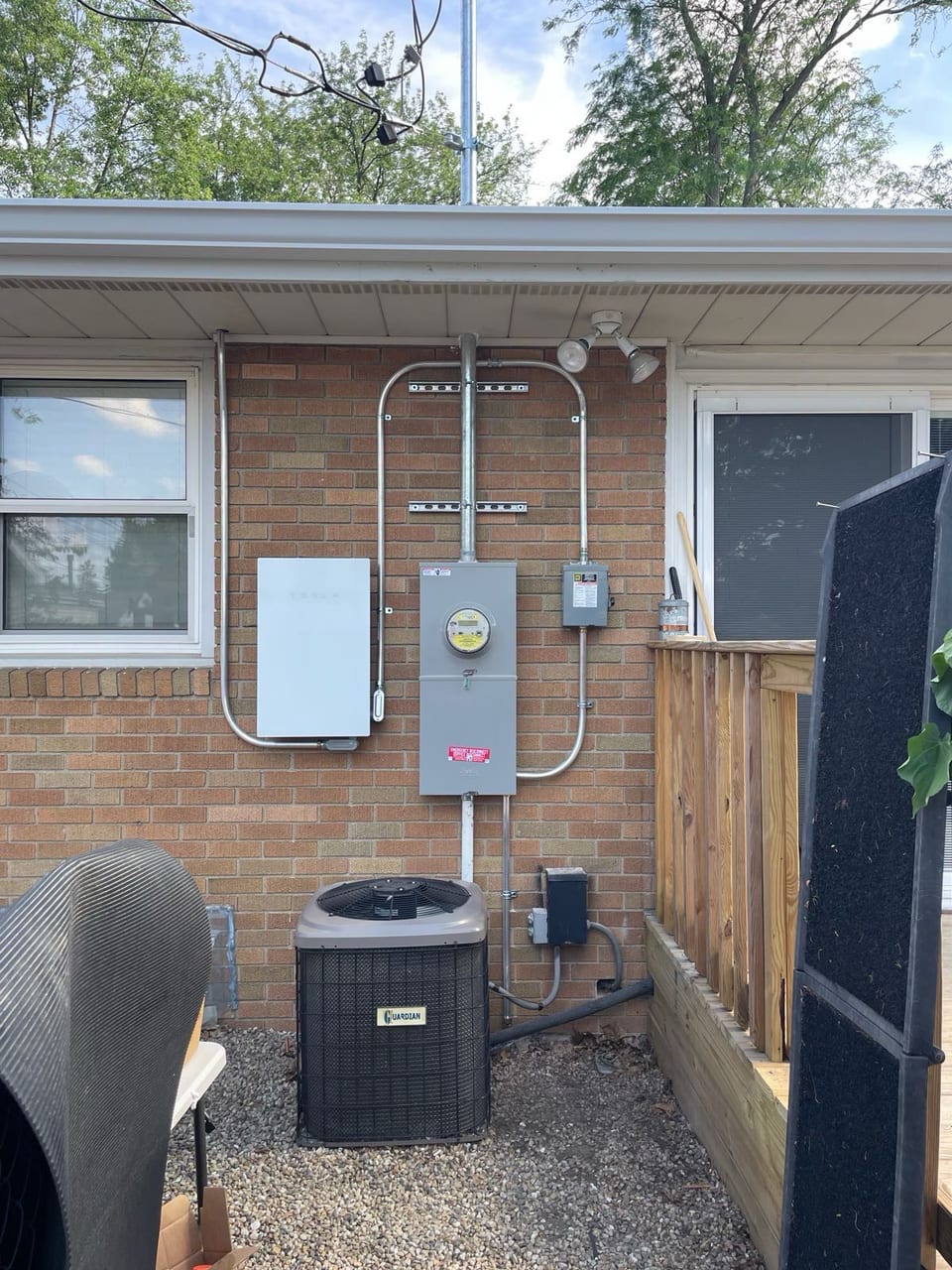 Solar electrical equipment mounted on a brick wall beside an air conditioning unit