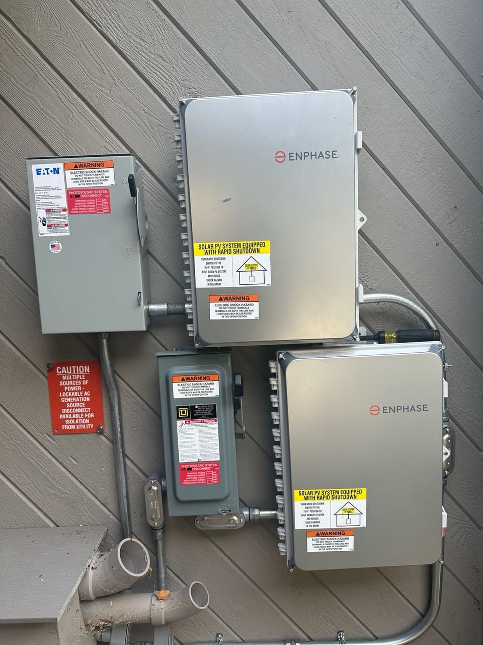 Close view of solar inverters and disconnect boxes on a home exterior