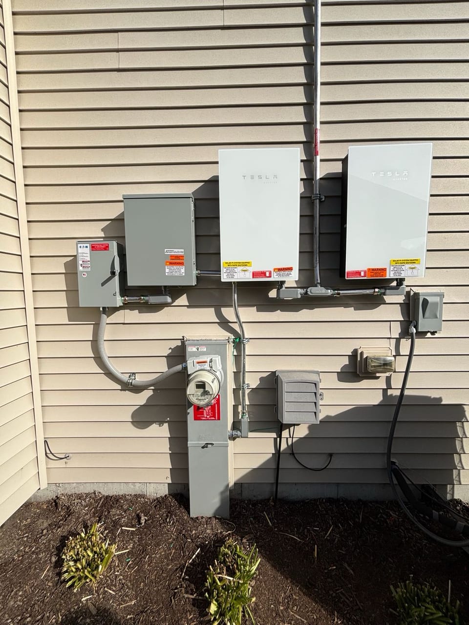 Solar inverters and utility meter installed on a home exterior wall