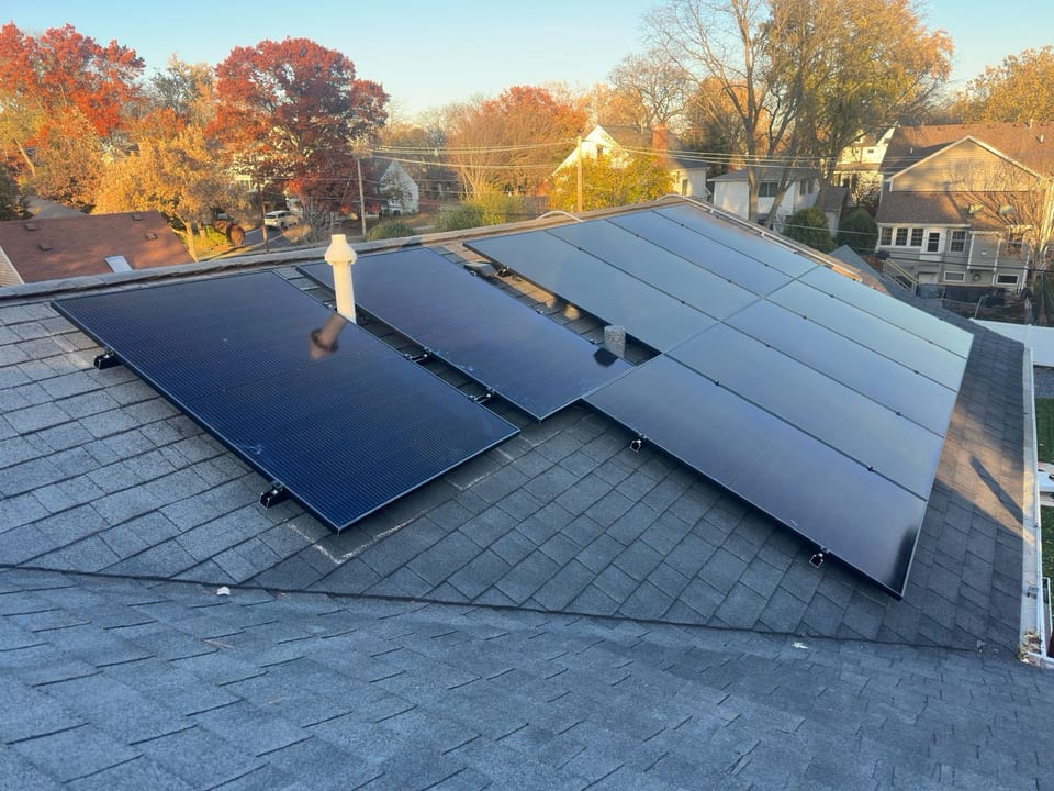Solar panel array on a shingle roof framed by autumn foliage