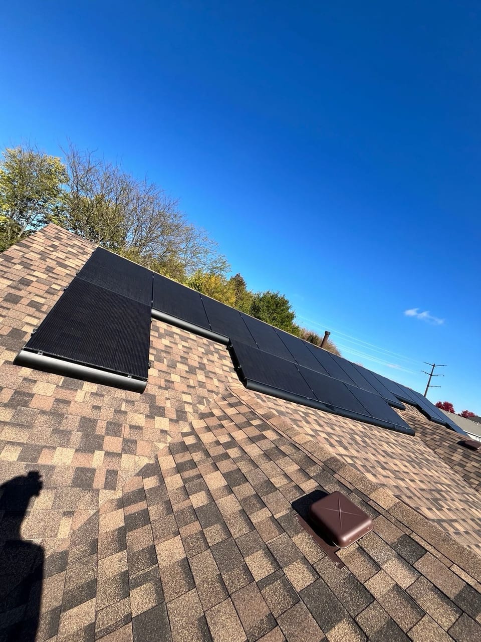 Solar panel array on a shingle roof beneath a deep blue sky