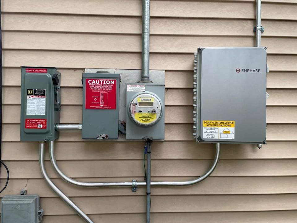 Close view of a utility meter, disconnect, and solar inverter