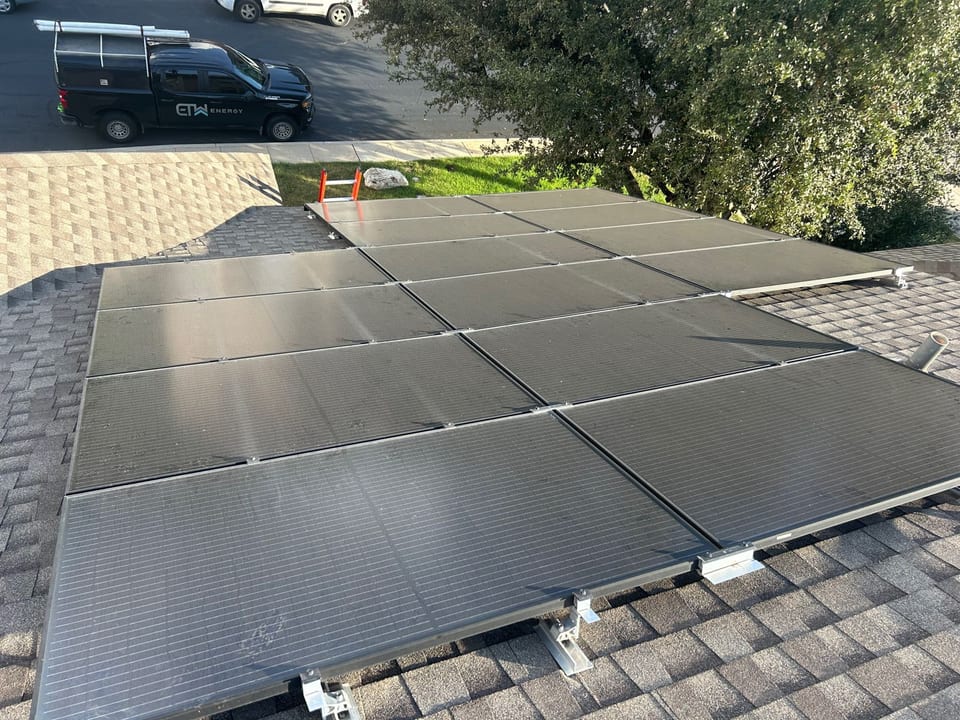 Rooftop solar array with an ETW Energy work truck parked at the curb below