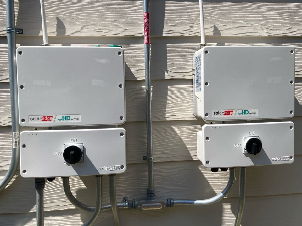 Two SolarEdge inverters and their disconnects mounted on a home’s siding