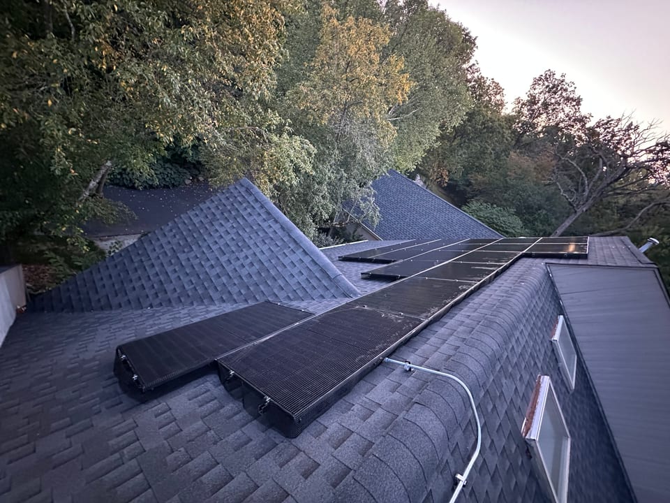 Rooftop solar array viewed from above, surrounded by trees